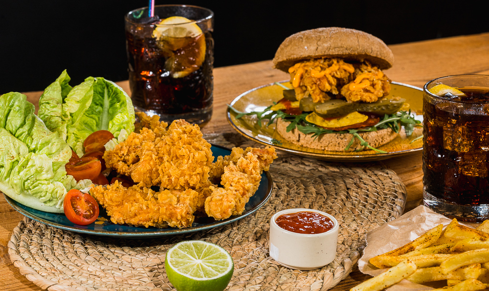 dos platos con comida de pollo con nuggets y una hamburguesa