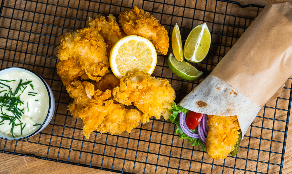 pollo empanado y crujiente con salsa blanca y un wrap a la derecha