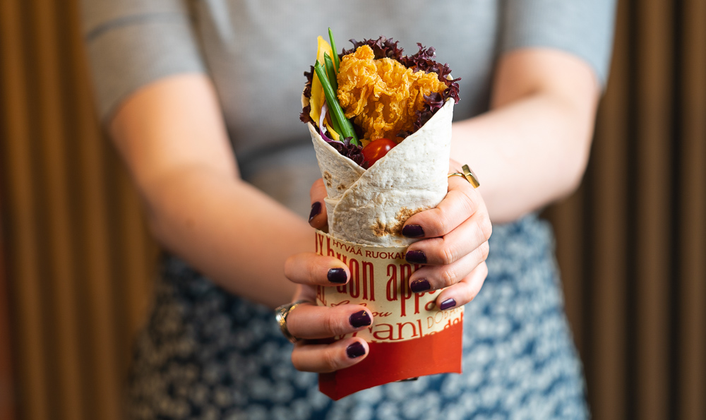un wrap colorido de pollo las manos con uñas pintadas 