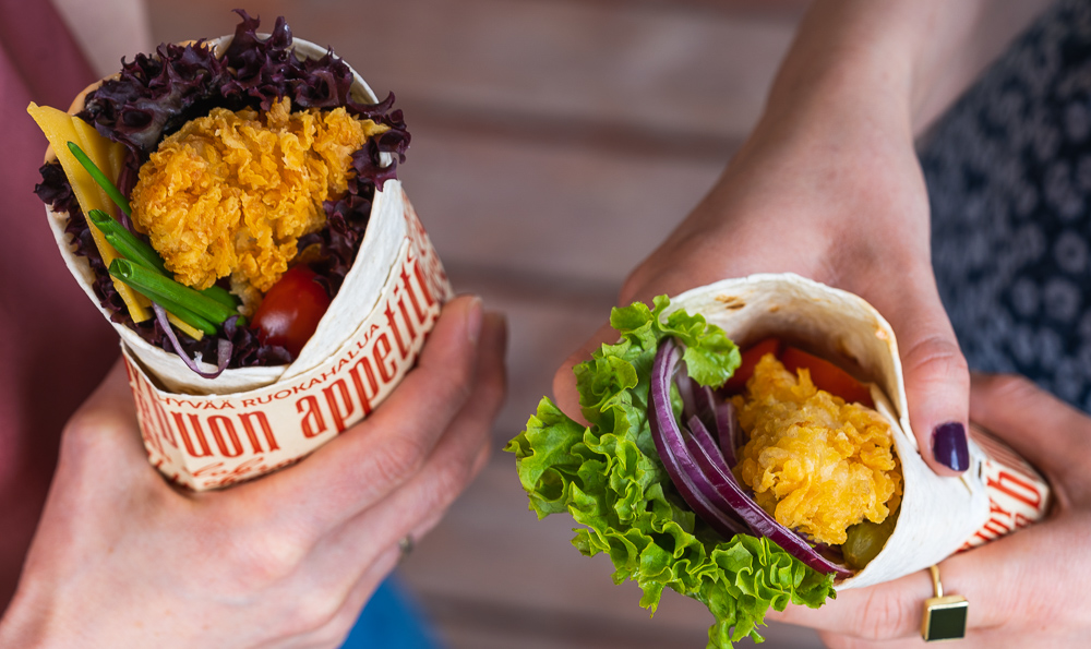 dos wraps con pollo y verduras en las manos