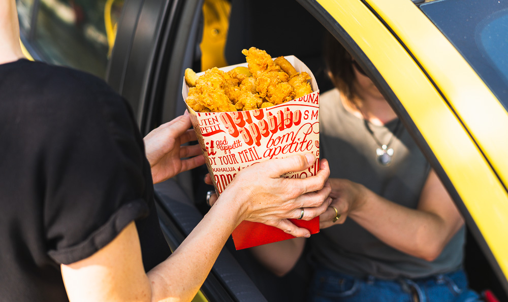 envase comida para llevar dos personas junto al coche con envase de pollo