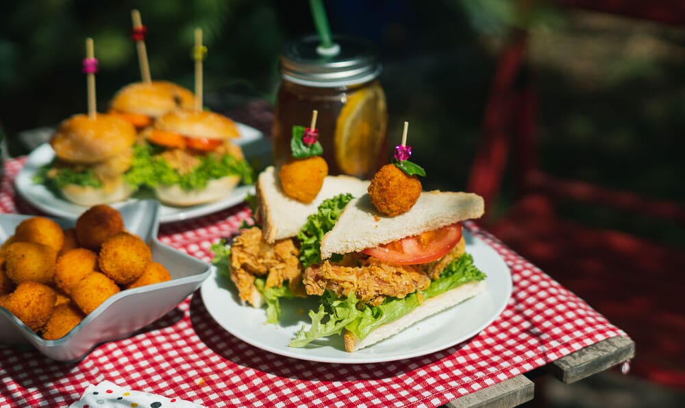 3 platos en la mesa con tapas y pequeños bocadillos con una limonada al fondo