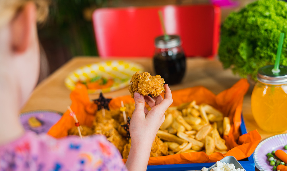 una chica toma un nuggets en la mano