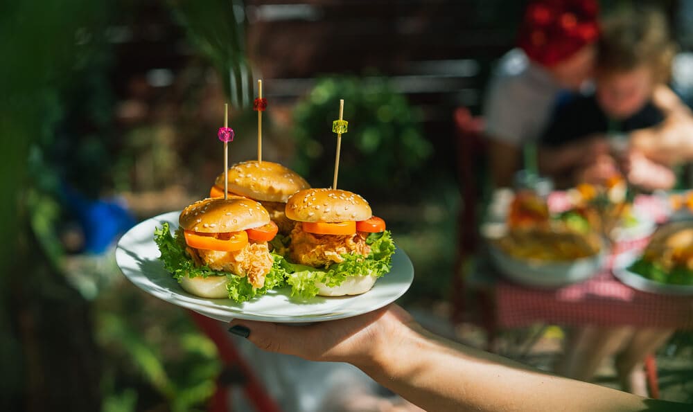 un plato con hamburguesas pequeñas en la mano