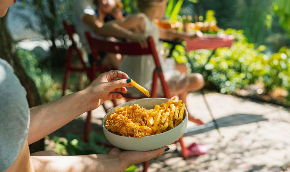 un bol lleno de patatas fritas y pollo rebozado en la mano