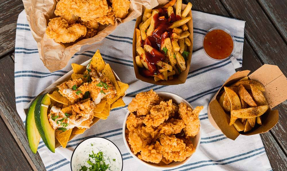 como hacer tiras de pollo kfc una mesa llena de comida deliciosa como patatas fritas, pollo empanado con salsas distintas