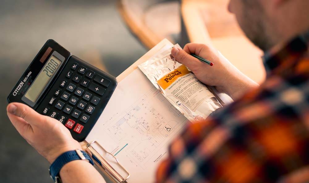 una calculadora en las manos con hojas y boli