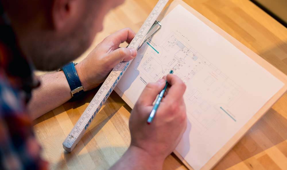 un hombre planeando con una hoja, un lápiz y una regla