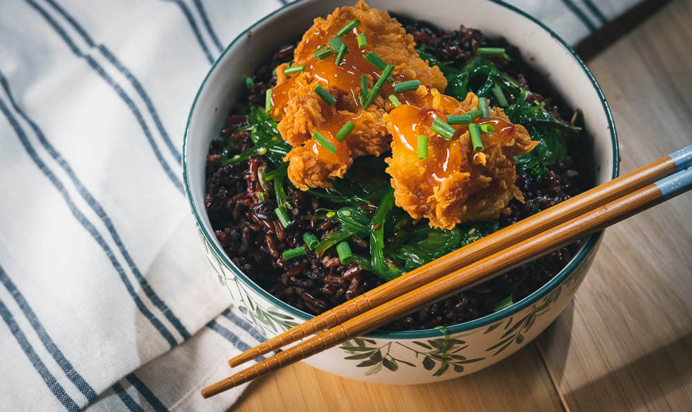 un cuenco con arroz salvaje, pollo rebozado y salsa 