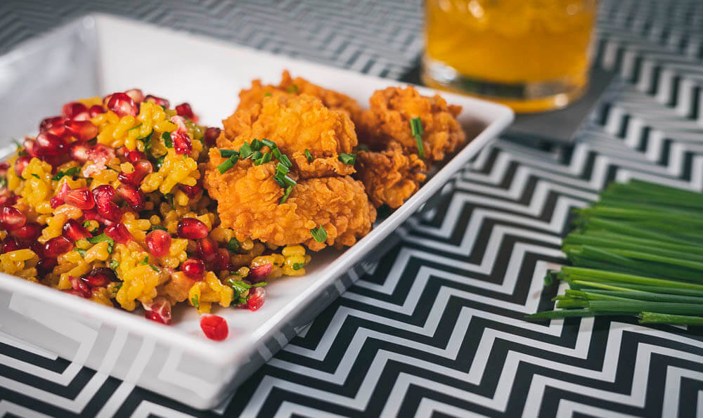 un plato con arroz, granada y pollo frito
