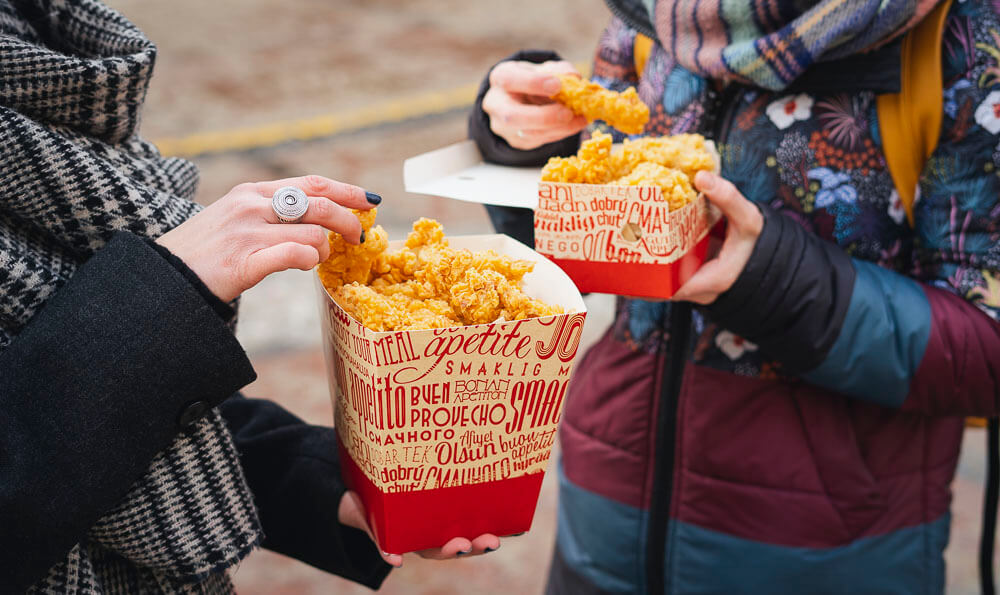 street food dos personas comiendo pollo rebozado de cubos de papel
